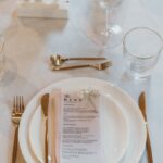 Beautifully arranged table setting with gold cutlery and menus for a wedding reception.