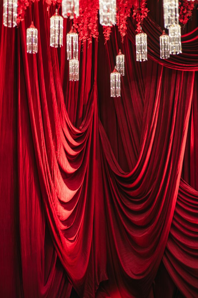 Stunning red drapery adorned with crystal chandeliers, perfect for luxurious interior decor.
