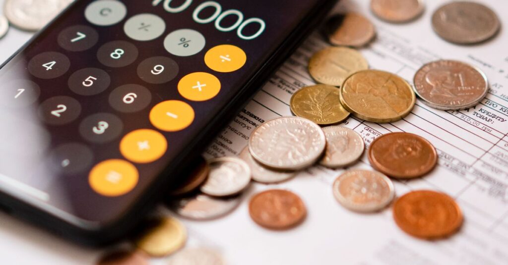 Smartphone calculator app displaying 10000 amidst scattered coins and documents.