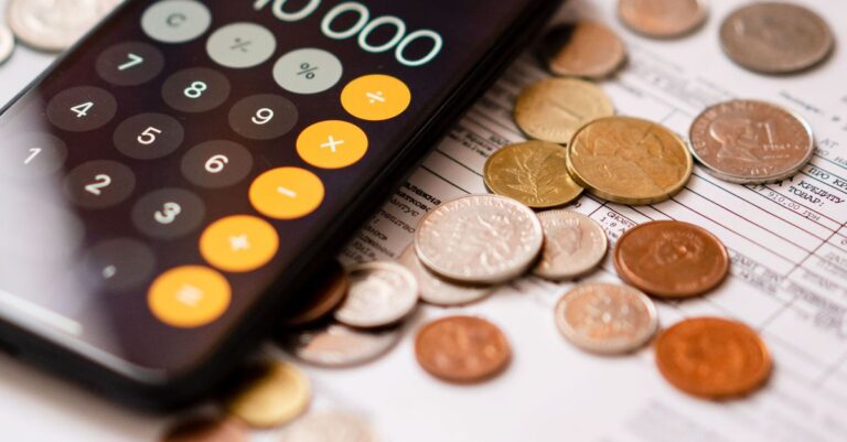 Smartphone calculator app displaying 10000 amidst scattered coins and documents.
